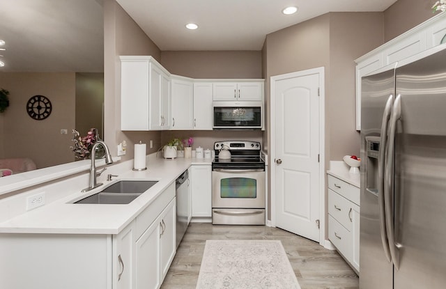 604 SE 18th St, Grimes, IA 50111 - kitchen with appliances with stainless steel finishes, a sink, a peninsula, white cabinetry, and light wood-type flooring