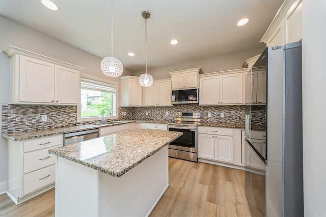 1454 S Sugar Creek Ct, West Des Moines, IA 50266 - kitchen featuring appliances with stainless steel finishes, a sink, light wood-style floors, a center island, and light stone counters