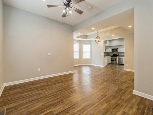 601 S 3rd Ave E, Newton, IA 50208 - unfurnished living room with dark wood-type flooring, baseboards, a ceiling fan, recessed lighting, and a raised ceiling