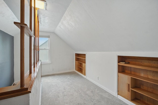 7105 Madison Ave, Urbandale, IA 50322 - bonus room featuring carpet floors, vaulted ceiling, baseboards, and built in shelves