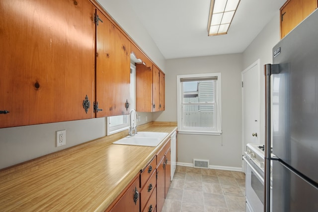 7105 Madison Ave, Urbandale, IA 50322 - kitchen with white appliances, a sink, brown cabinetry, and light countertops