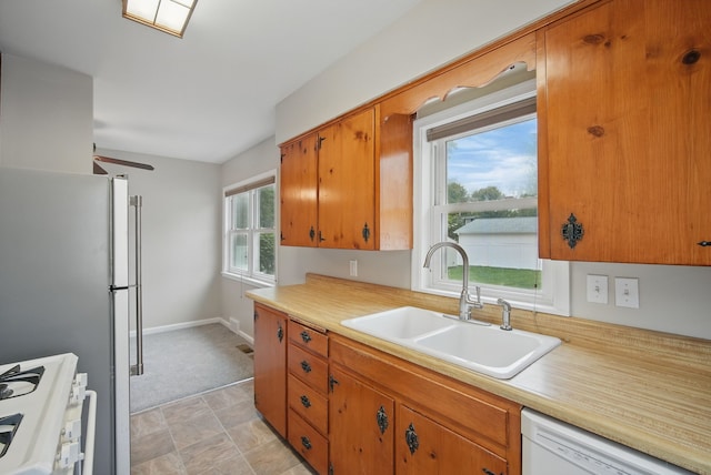 7105 Madison Ave, Urbandale, IA 50322 - kitchen with white dishwasher, a sink, stove, and light countertops