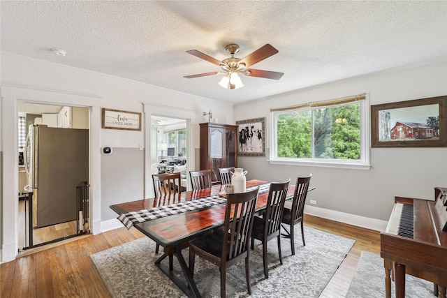 2419 30th St, Des Moines, IA 50310 - dining space featuring a textured ceiling, a ceiling fan, baseboards, and light wood-type flooring