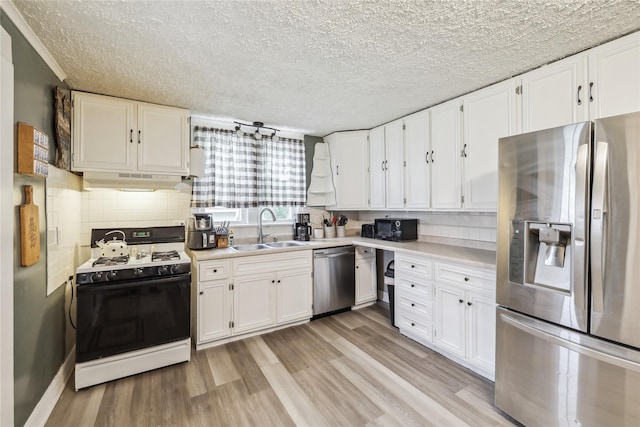 2419 30th St, Des Moines, IA 50310 - kitchen featuring stainless steel appliances, a sink, light wood-type flooring, white cabinets, and a textured ceiling