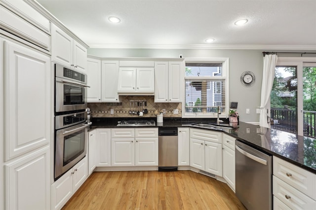 6909 Capitol View Ct, Johnston, IA 50131 - kitchen featuring appliances with stainless steel finishes, a sink, ornamental molding, healthy amount of natural light, and white cabinets