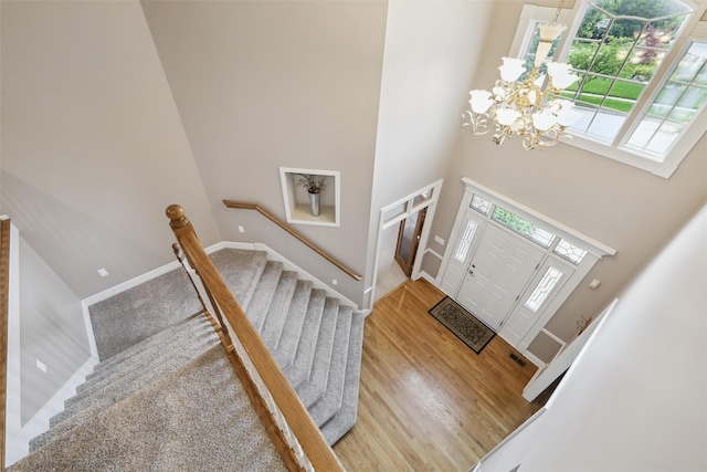 6909 Capitol View Ct, Johnston, IA 50131 - entryway featuring a chandelier, a high ceiling, stairs, wood finished floors, and baseboards