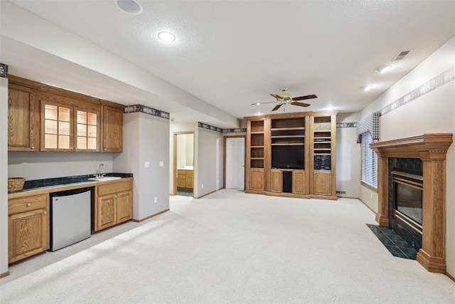 6909 Capitol View Ct, Johnston, IA 50131 - kitchen with dishwasher, a tiled fireplace, a sink, brown cabinets, and a ceiling fan