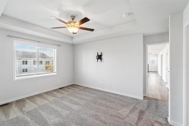 580 NW Rosemont Dr, Waukee, IA 50263 - empty room featuring a raised ceiling, carpet floors, plenty of natural light, and a ceiling fan