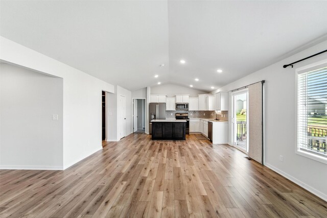 580 NW Rosemont Dr, Waukee, IA 50263 - unfurnished living room with vaulted ceiling, light wood-style flooring, plenty of natural light, and recessed lighting