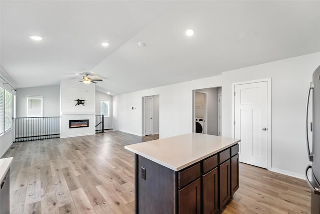 580 NW Rosemont Dr, Waukee, IA 50263 - kitchen with ceiling fan, washer / dryer, vaulted ceiling, dark brown cabinets, and light wood finished floors
