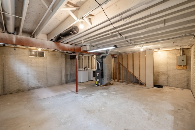 1540 8th St, Des Moines, IA 50314 - unfinished basement featuring electric panel, heating unit, washer and clothes dryer, and brick wall