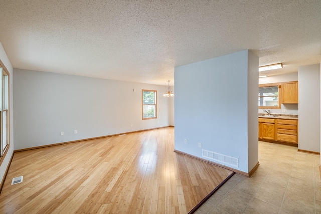 1540 8th St, Des Moines, IA 50314 - empty room featuring a chandelier, a textured ceiling, and light wood-style flooring