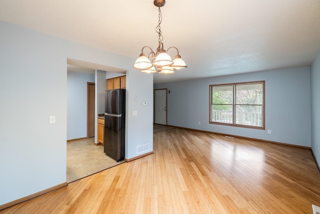1540 8th St, Des Moines, IA 50314 - empty room featuring a chandelier and light wood finished floors