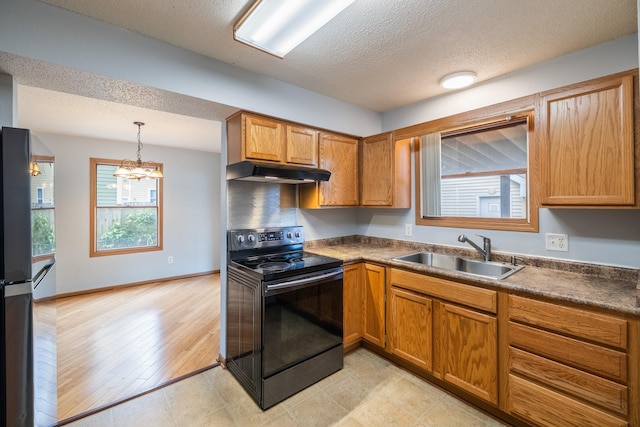 1540 8th St, Des Moines, IA 50314 - kitchen with electric range, under cabinet range hood, dark countertops, a chandelier, and brown cabinets