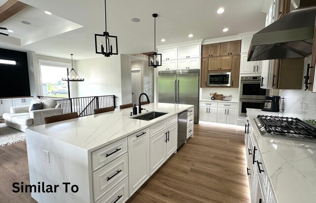1410 NW Bull Run Ct, Waukee, IA 50263 - kitchen with built in appliances, exhaust hood, a sink, wood finished floors, and recessed lighting