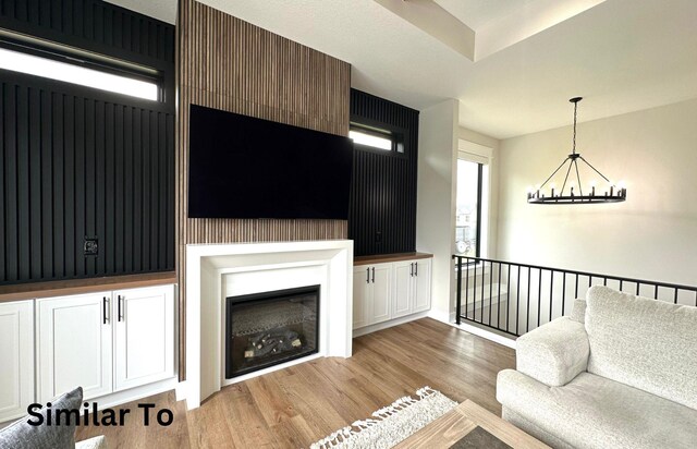 1410 NW Bull Run Ct, Waukee, IA 50263 - living room featuring light wood-type flooring, a chandelier, and a glass covered fireplace