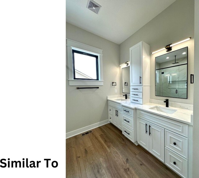 1410 NW Bull Run Ct, Waukee, IA 50263 - bathroom with double vanity, baseboards, a stall shower, and wood finished floors
