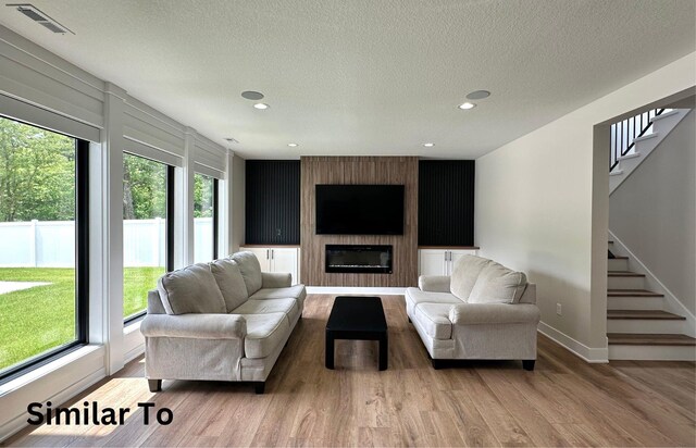 1410 NW Bull Run Ct, Waukee, IA 50263 - living area with wood finished floors, stairs, healthy amount of natural light, baseboards, and a textured ceiling