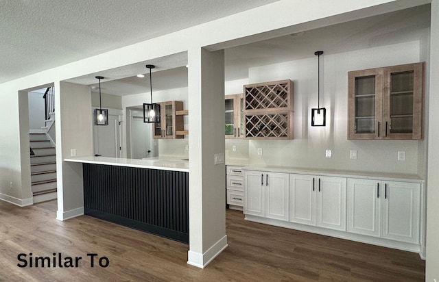 1410 NW Bull Run Ct, Waukee, IA 50263 - kitchen with glass insert cabinets, dark wood-style floors, hanging light fixtures, and baseboards