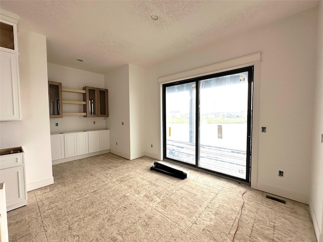 1410 NW Bull Run Ct, Waukee, IA 50263 - unfurnished dining area featuring a textured ceiling and baseboards
