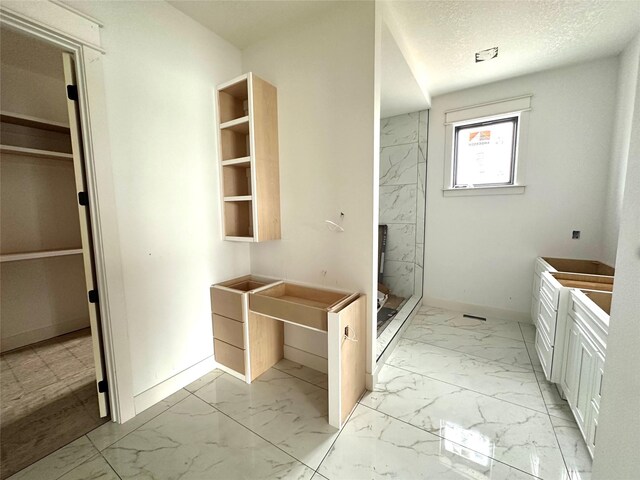 1410 NW Bull Run Ct, Waukee, IA 50263 - full bath with marble look tiles, a shower stall, a walk in closet, vanity, and baseboards