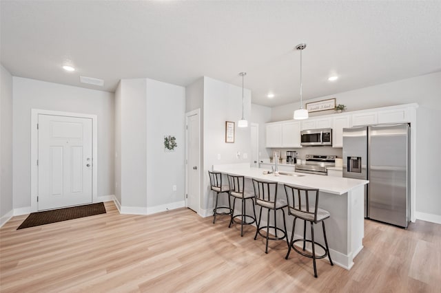 714 Umbra Pl, Norwalk, IA 50211 - kitchen featuring stainless steel appliances, a sink, a kitchen bar, light wood finished floors, and light countertops
