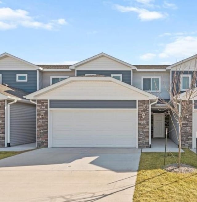 714 Umbra Pl, Norwalk, IA 50211 - view of property featuring driveway, an attached garage, stone siding, and a front lawn