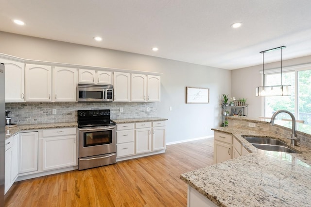 1625 S 50th Pl, West Des Moines, IA 50265 - kitchen with appliances with stainless steel finishes, a sink, backsplash, light wood-style flooring, and recessed lighting