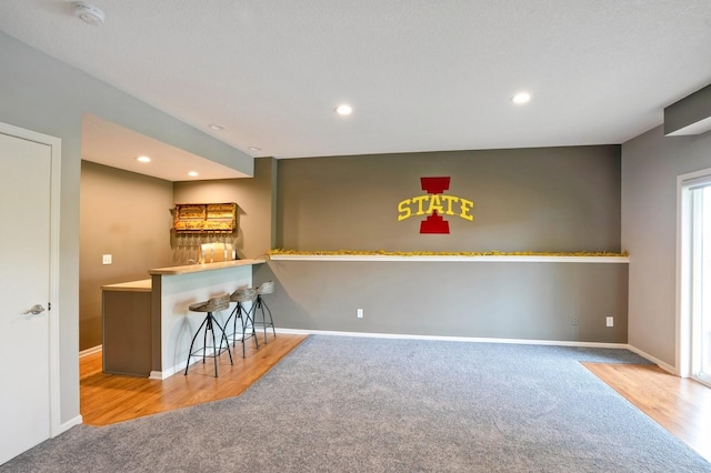 1625 S 50th Pl, West Des Moines, IA 50265 - kitchen featuring carpet floors, baseboards, recessed lighting, a kitchen bar, and wood finished floors