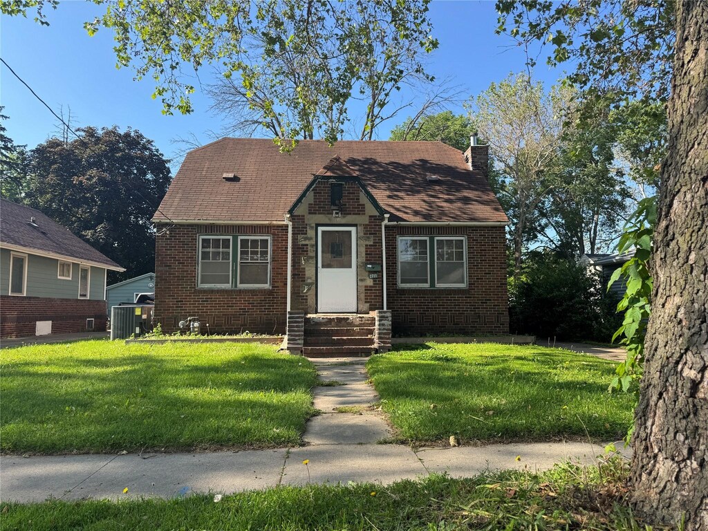2711 Des Moines St, Des Moines, IA 50317 - view of front of home featuring brick siding, a front lawn, a chimney, and roof with shingles