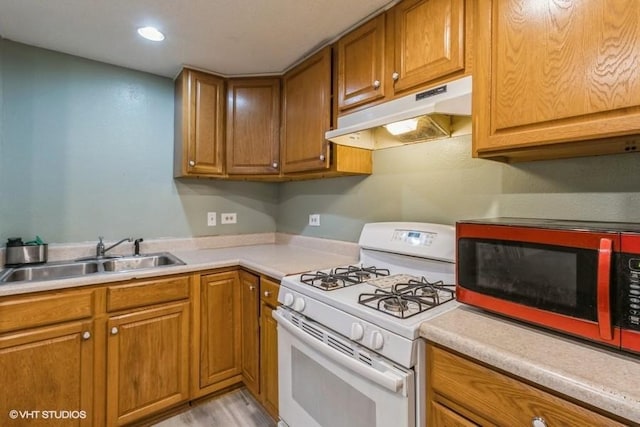 201 Main St, New Virginia, IA 50210 - kitchen featuring white gas stove, under cabinet range hood, a sink, brown cabinetry, and recessed lighting