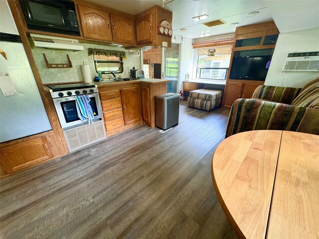 3170 Morman Trl, Ellston, IA 50074 - kitchen with black microwave, oven, under cabinet range hood, dark wood-type flooring, and an AC wall unit