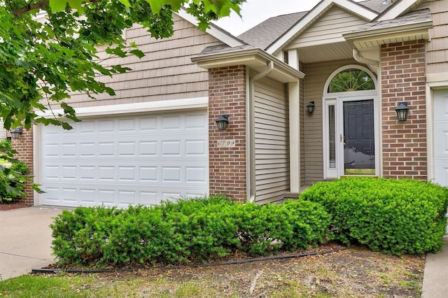 6799 NW 57th St, Johnston, IA 50131 - property entrance featuring brick siding, an attached garage, and driveway