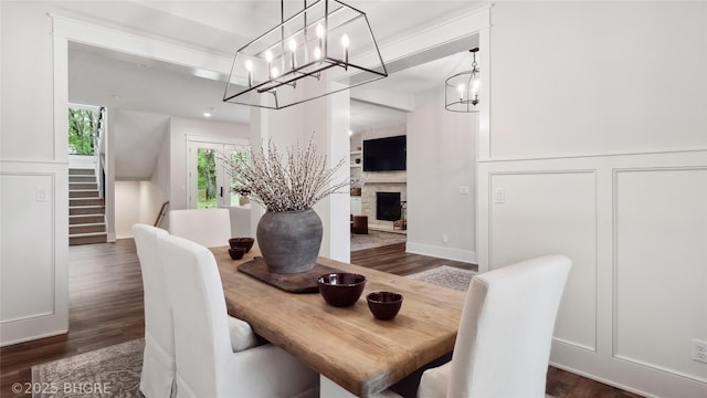 815 S Kingswood Ct, West Des Moines, IA 50266 - dining area featuring a decorative wall, dark wood-style floors, a chandelier, stairs, and a fireplace
