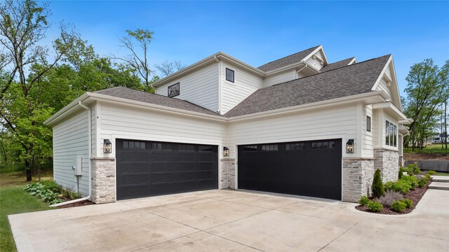 815 S Kingswood Ct, West Des Moines, IA 50266 - view of home's exterior featuring an attached garage, driveway, stone siding, and roof with shingles