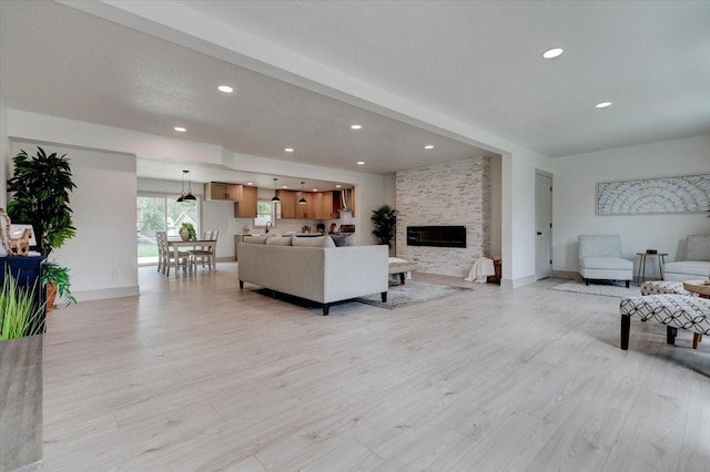 801 SE 5th St, Grimes, IA 50111 - living room with light wood-style flooring, a stone fireplace, recessed lighting, and baseboards