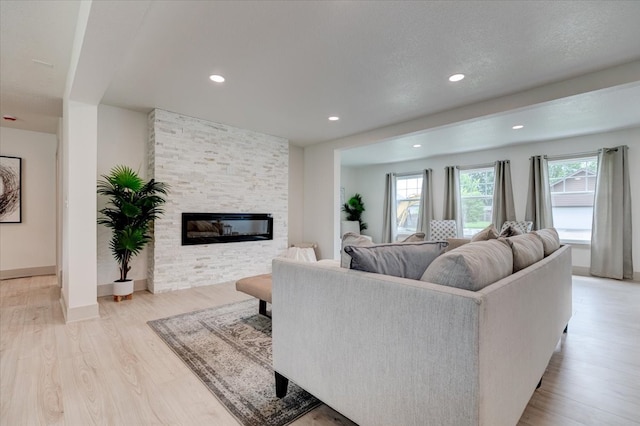 801 SE 5th St, Grimes, IA 50111 - living room featuring light wood-style floors, recessed lighting, a stone fireplace, and baseboards