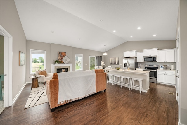 9334 Valley Pkwy, Johnston, IA 50131 - living room featuring lofted ceiling, dark wood-style floors, a tiled fireplace, and recessed lighting