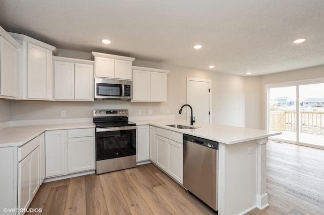 2925 6th Ave SW, Altoona, IA 50009 - kitchen with appliances with stainless steel finishes, a sink, light wood-style flooring, recessed lighting, and a peninsula