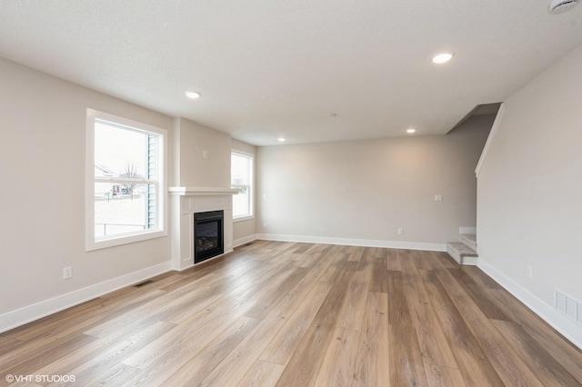 2925 6th Ave SW, Altoona, IA 50009 - unfurnished living room featuring a glass covered fireplace, light wood-type flooring, recessed lighting, stairway, and baseboards