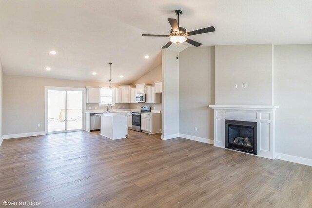 3002 6th Ave SW, Altoona, IA 50009 - unfurnished living room with a sink, a ceiling fan, light wood-type flooring, baseboards, and lofted ceiling