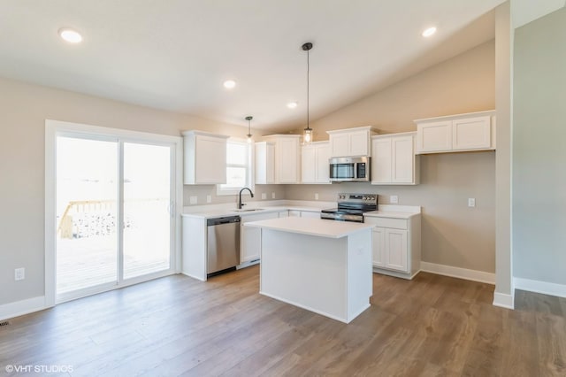 3002 6th Ave SW, Altoona, IA 50009 - kitchen featuring stainless steel appliances, a sink, white cabinetry, vaulted ceiling, and a kitchen island