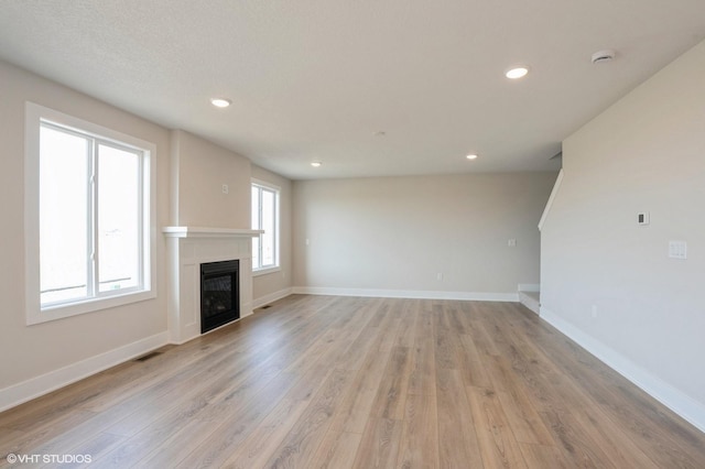 3010 6th Ave SW, Altoona, IA 50009 - unfurnished living room featuring a glass covered fireplace, light wood-style floors, baseboards, and recessed lighting
