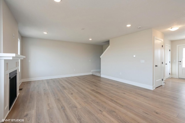 3010 6th Ave SW, Altoona, IA 50009 - unfurnished living room featuring a fireplace, light wood-style floors, recessed lighting, and baseboards