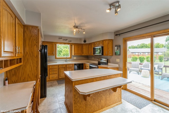 408 W 13th St N, Newton, IA 50208 - kitchen with black appliances, light countertops, a sink, a center island, and brown cabinetry