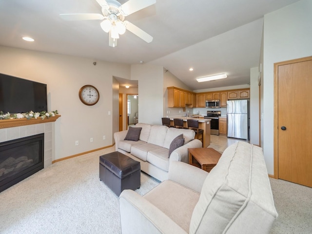 1355 SE 6th St Unit 301, Grimes, IA 50111 - living area featuring vaulted ceiling, light colored carpet, a ceiling fan, a tiled fireplace, and baseboards