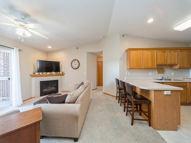 1355 SE 6th St Unit 301, Grimes, IA 50111 - kitchen with lofted ceiling, a kitchen breakfast bar, a tiled fireplace, a sink, and light countertops