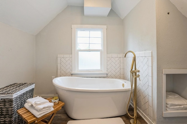 140 N 7th St, Carlisle, IA 50047 - bathroom featuring a soaking tub, lofted ceiling, and tile walls
