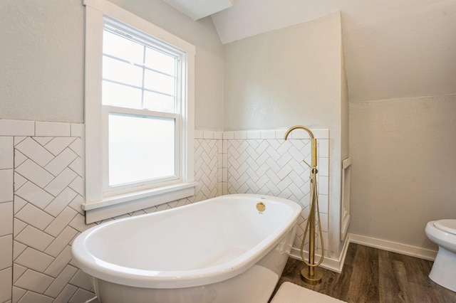 140 N 7th St, Carlisle, IA 50047 - full bathroom with tile walls, wood finished floors, a freestanding bath, toilet, and lofted ceiling