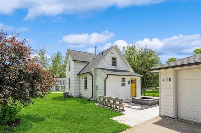 140 N 7th St, Carlisle, IA 50047 - back of property with roof with shingles, a yard, central AC, and a garage